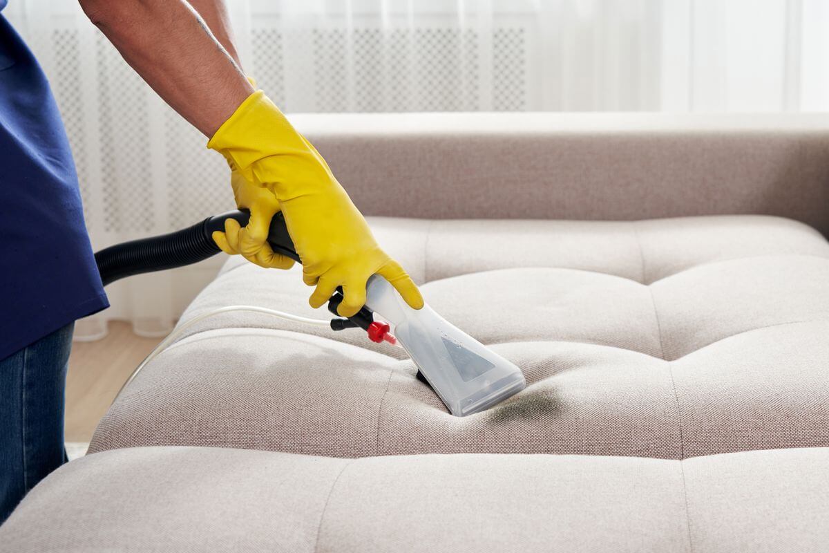 Profissional em processo de limpeza e higienização de sofá, garantindo revitalização e remoção de sujeiras.